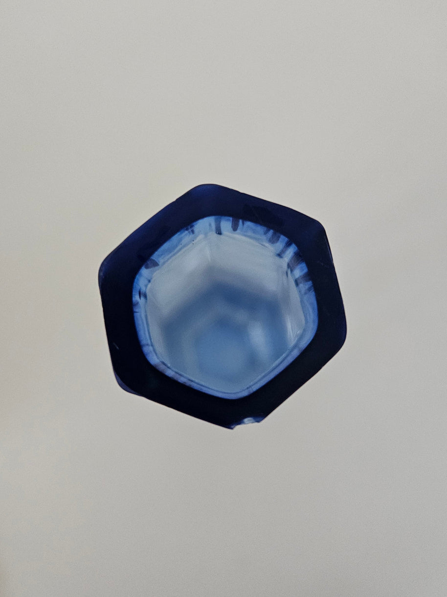 Top down view of a hexagonal blue glass vase on a white background