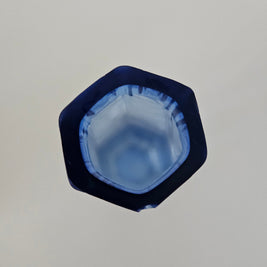 Top down view of a hexagonal blue glass vase on a white background