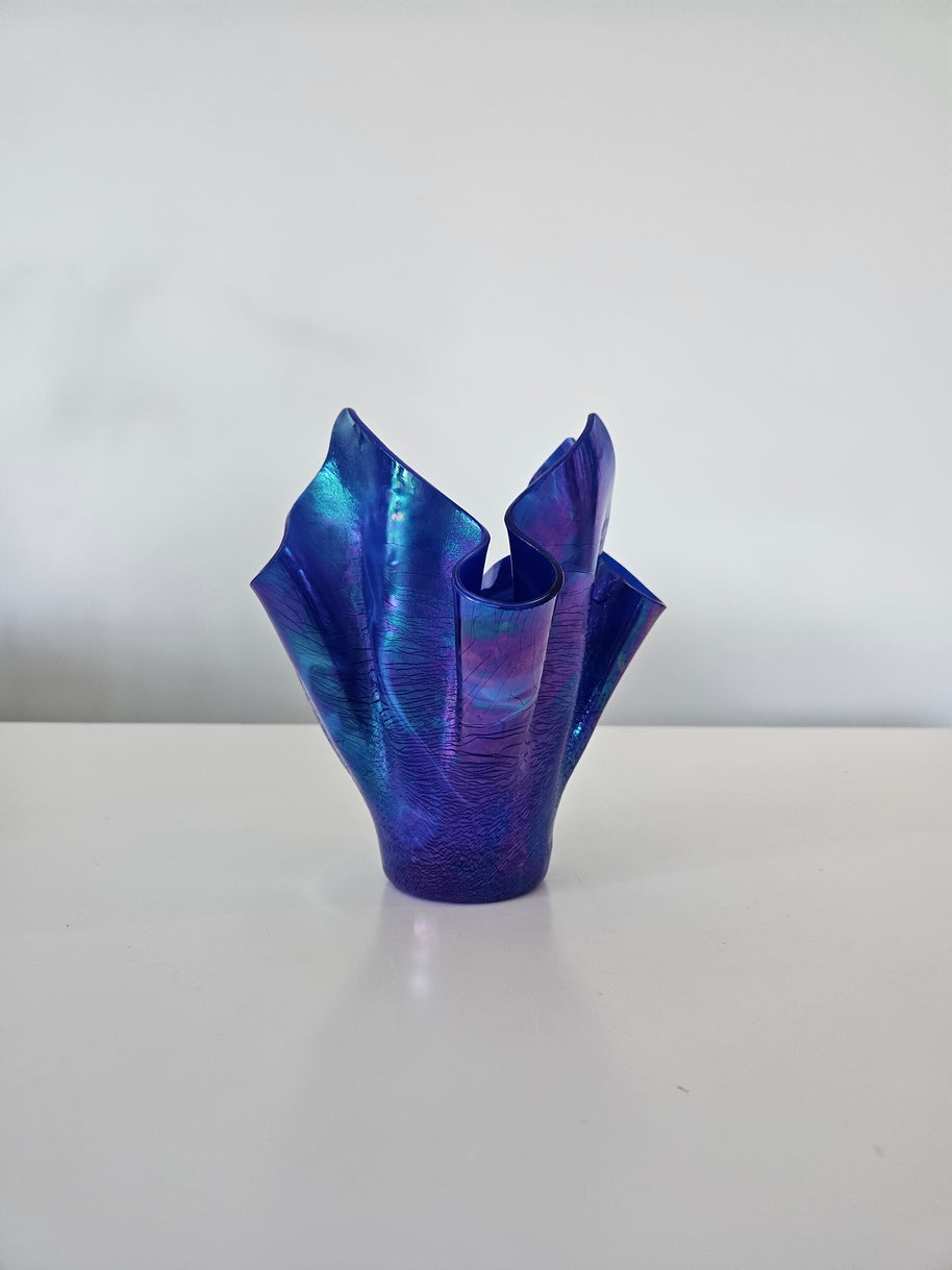 Side view of a blue and purple handkerchief style glass vase on a white background