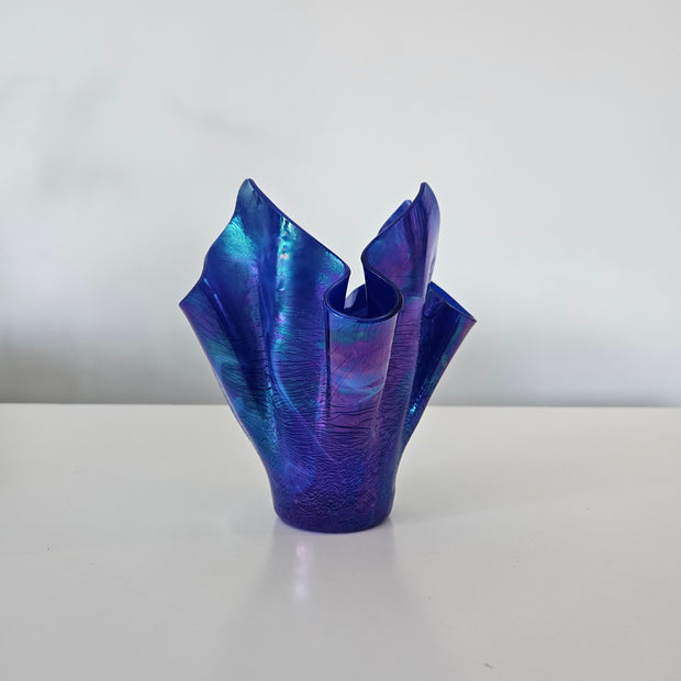 Side view of a blue and purple handkerchief style glass vase on a white background