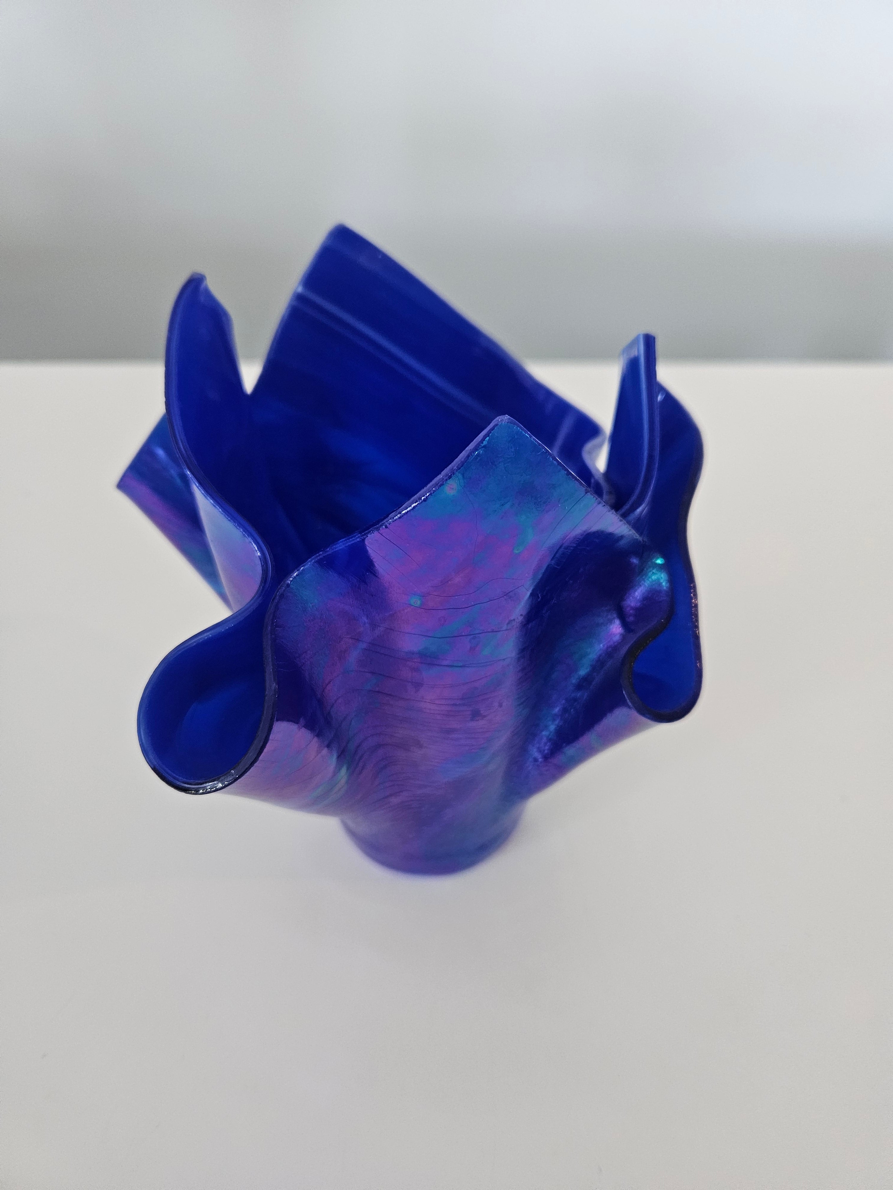 Side view of a blue and purple handkerchief glass vase on a white background