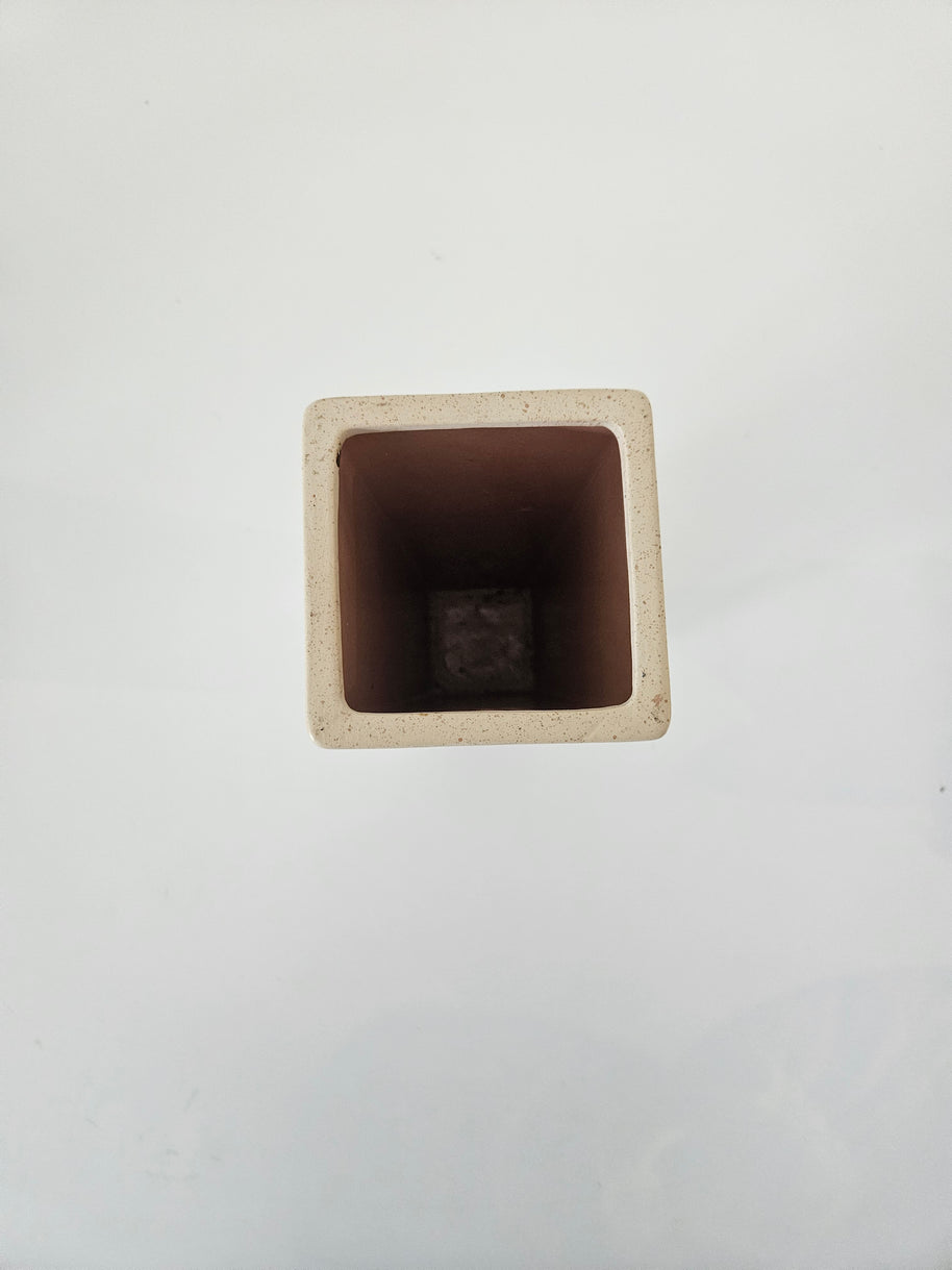 Top down view of a white square stone vase on a white background