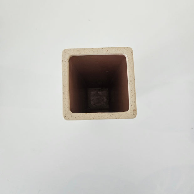 Top down view of a white square stone vase on a white background