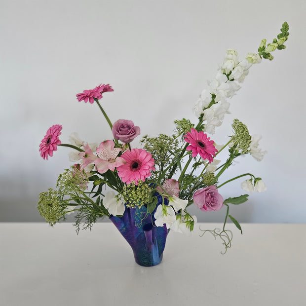 Floral arrangement with pink and white flowers in a blue vase against a white background
