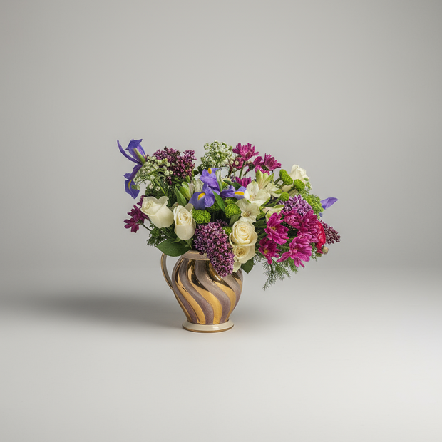Bouquet of flowers in a decorative gold and lilac vase on a grey background