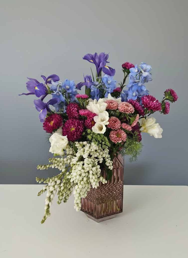 A flower arrangement in a mid-century modern dusty pink vase