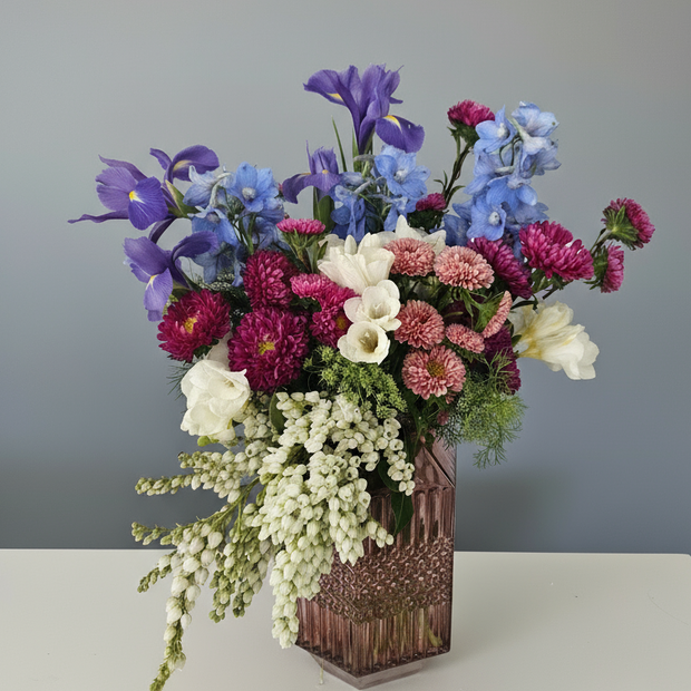 A flower arrangement in a mid-century modern dusty pink vase
