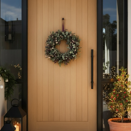 Front door with a wreath, candles, and a potted plant on a porch.