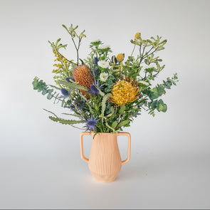 Decorative arrangement of flowers against a white wall.
