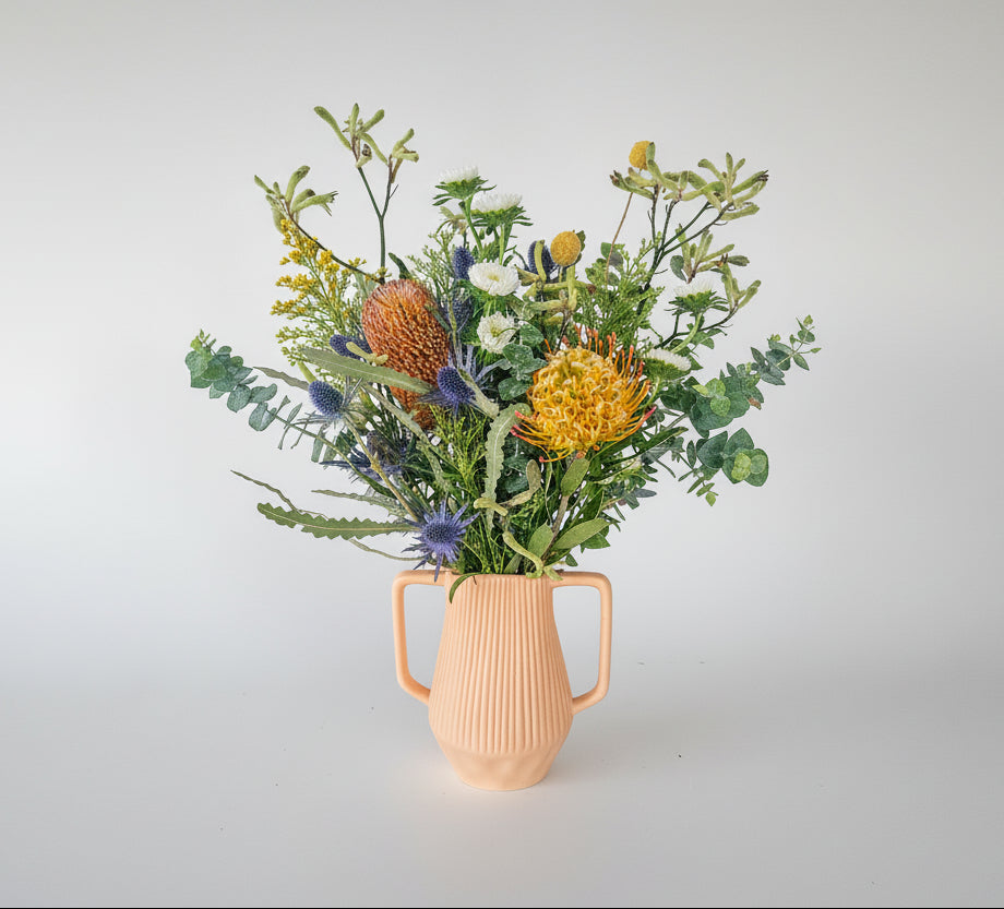 Decorative arrangement of flowers against a white wall.