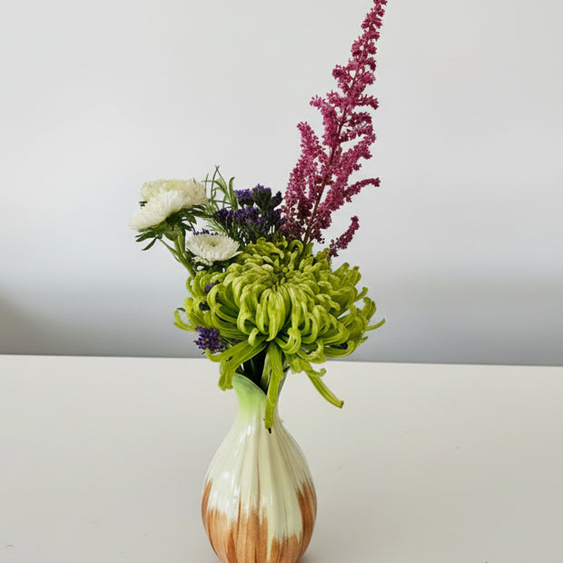 orange and white bud vase with flowers