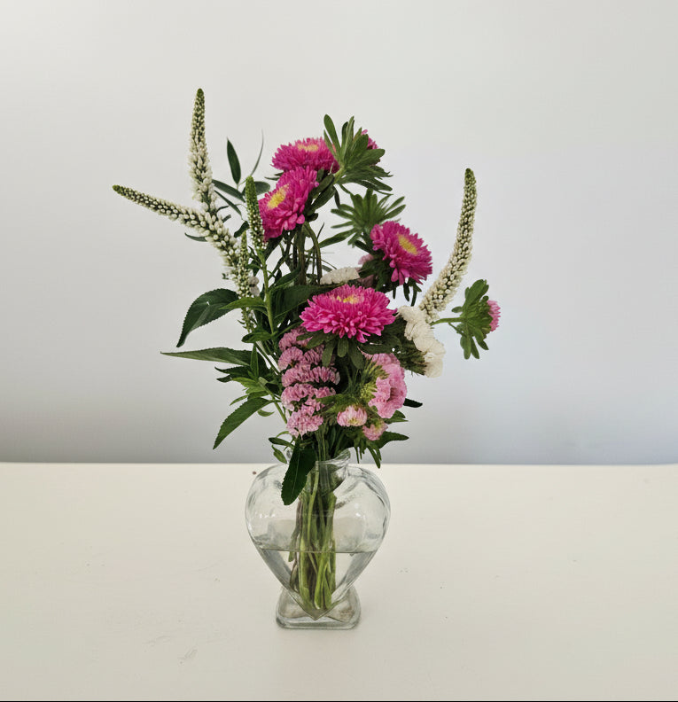 Bouquet of pink and white flowers in a clear glass vase on a white background
