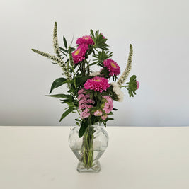 Bouquet of pink and white flowers in a clear glass vase on a white background