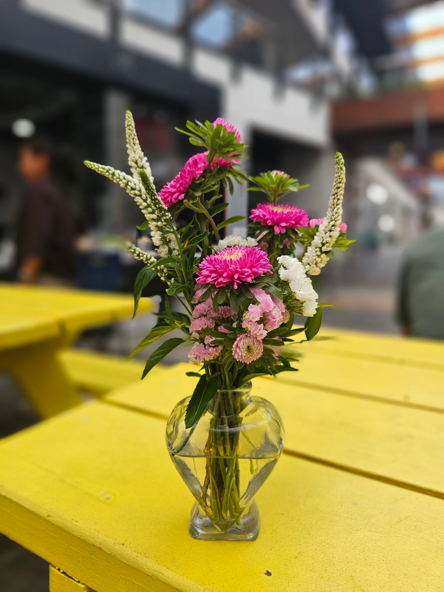Glass vase with pink and white flowers on a yellow table