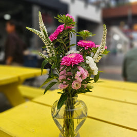 Glass vase with pink and white flowers on a yellow table