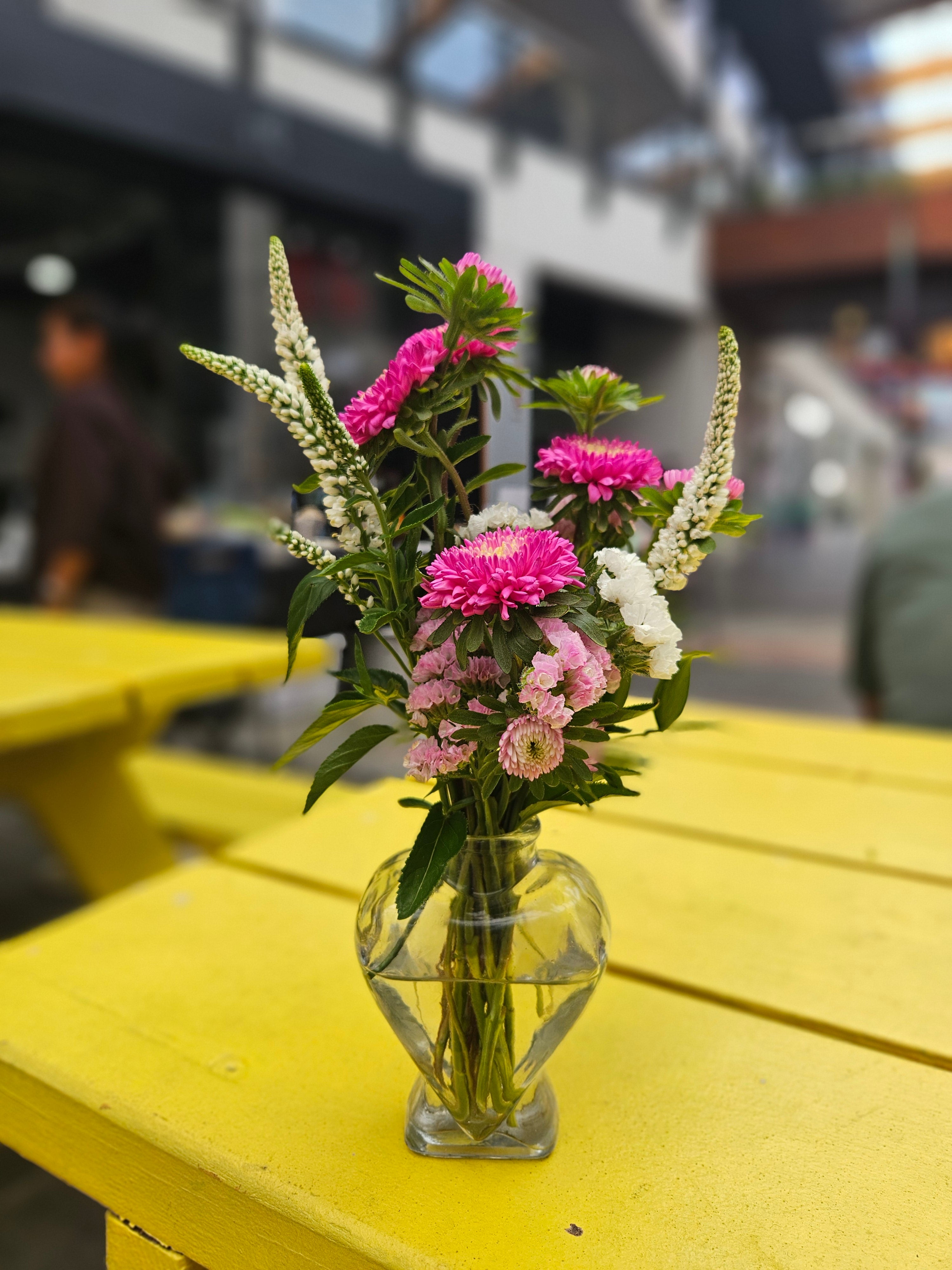 Glass vase with pink and white flowers on a yellow table