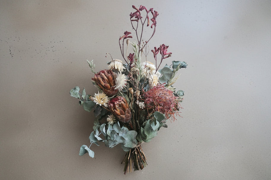 Bouquet of dried flowers and greenery on a beige surface