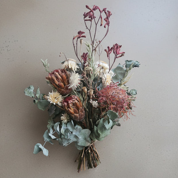Bouquet of dried flowers and greenery on a beige surface