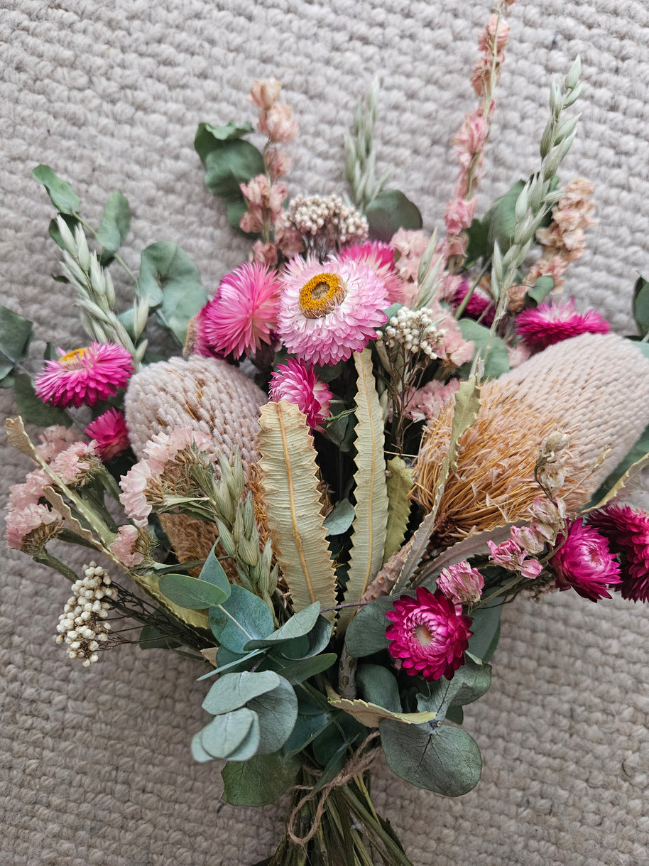 Bouquet of flowers with pink and green elements on a textured surface
