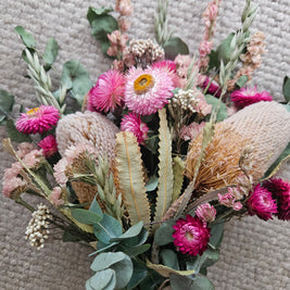 Bouquet of flowers with pink and green elements on a textured surface