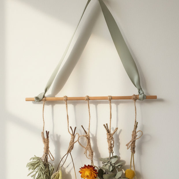 Decorative wall art with twigs and dried flowers on a plain background