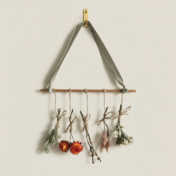 Decorative wall art made of twigs and dried flowers on a plain background