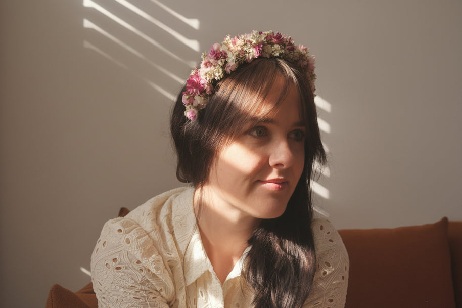 Woman with a floral headband sitting in a softly lit room.
