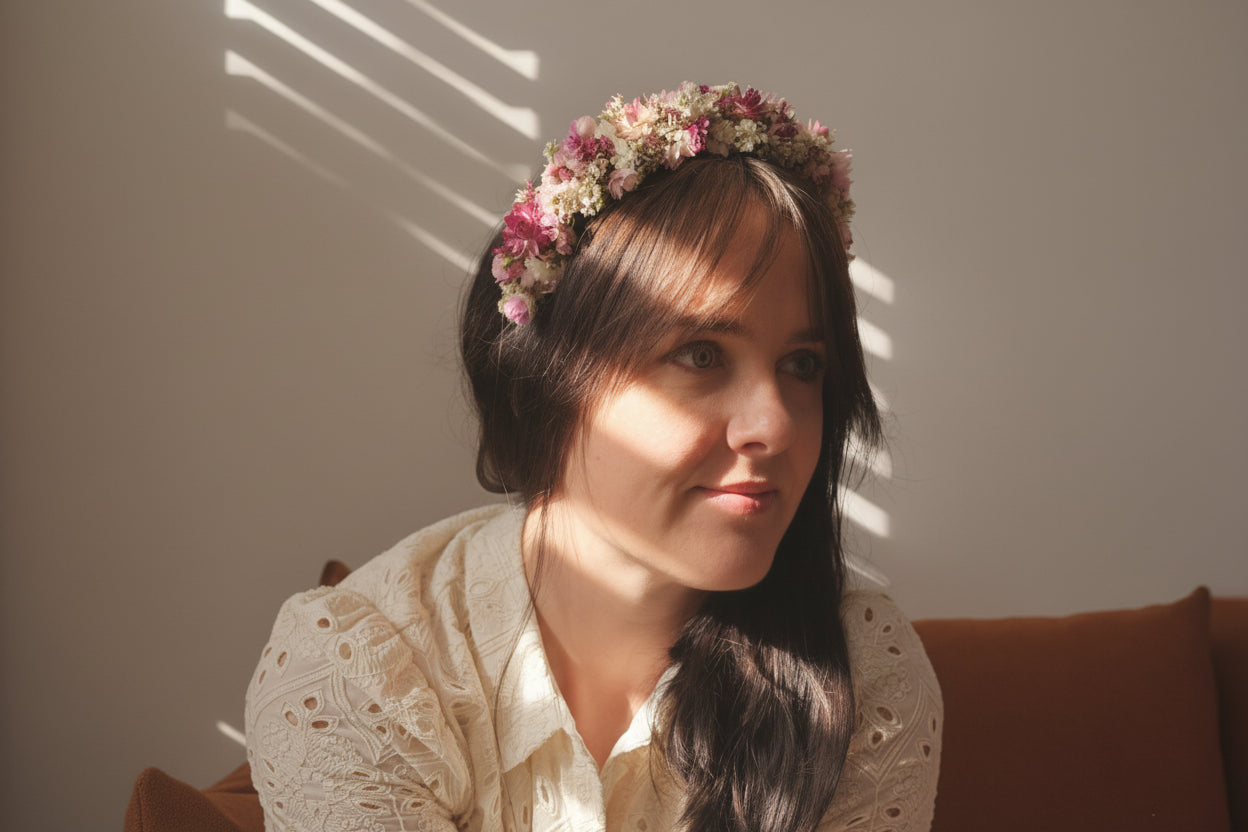 Woman with a floral headband sitting in a softly lit room.