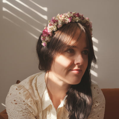 Woman with a floral headband sitting in a softly lit room.
