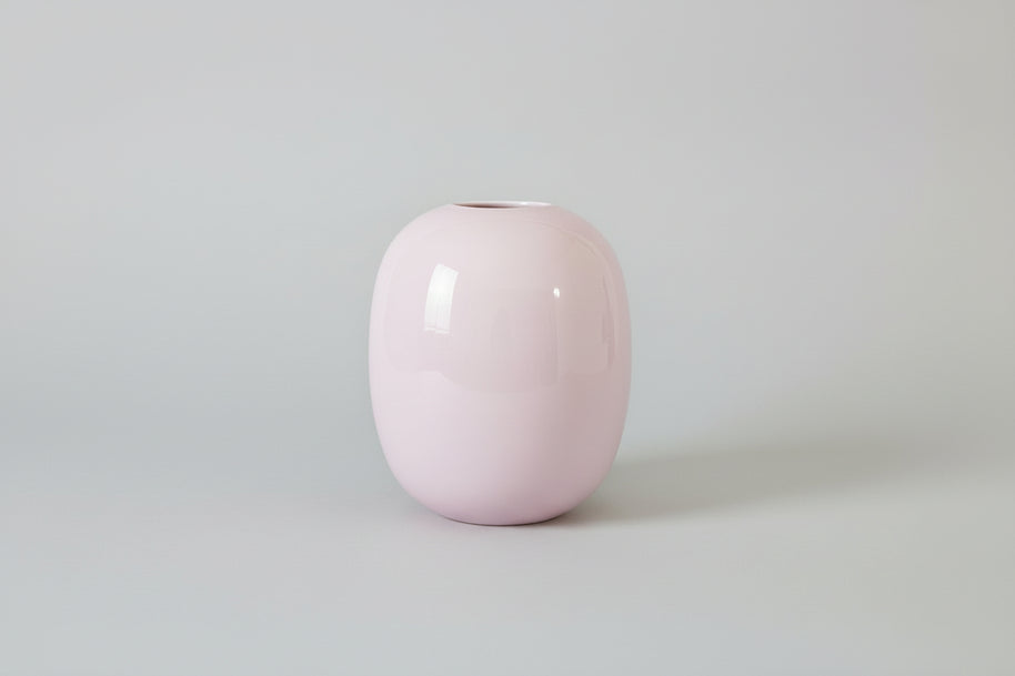Pink glass vase on a grey surface with a grey background