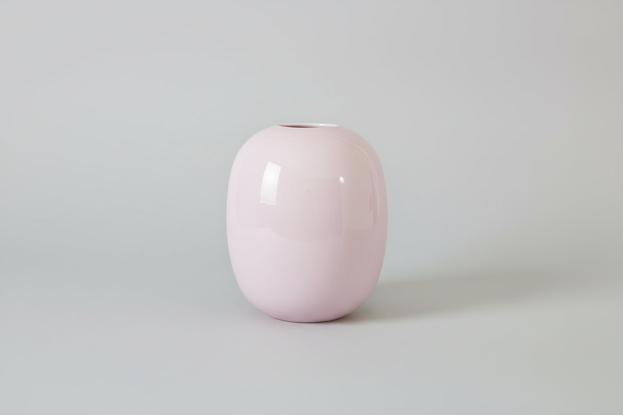 Pink glass vase on a grey surface with a grey background