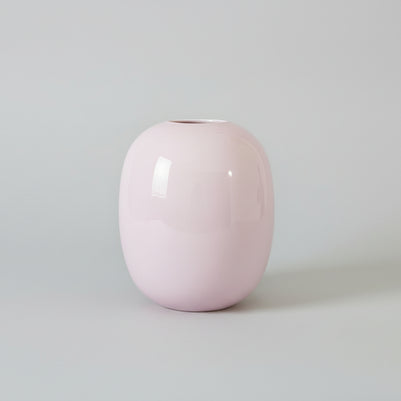 Pink glass vase on a grey surface with a grey background
