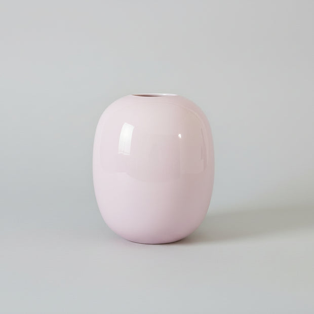 Pink glass vase on a grey surface with a grey background