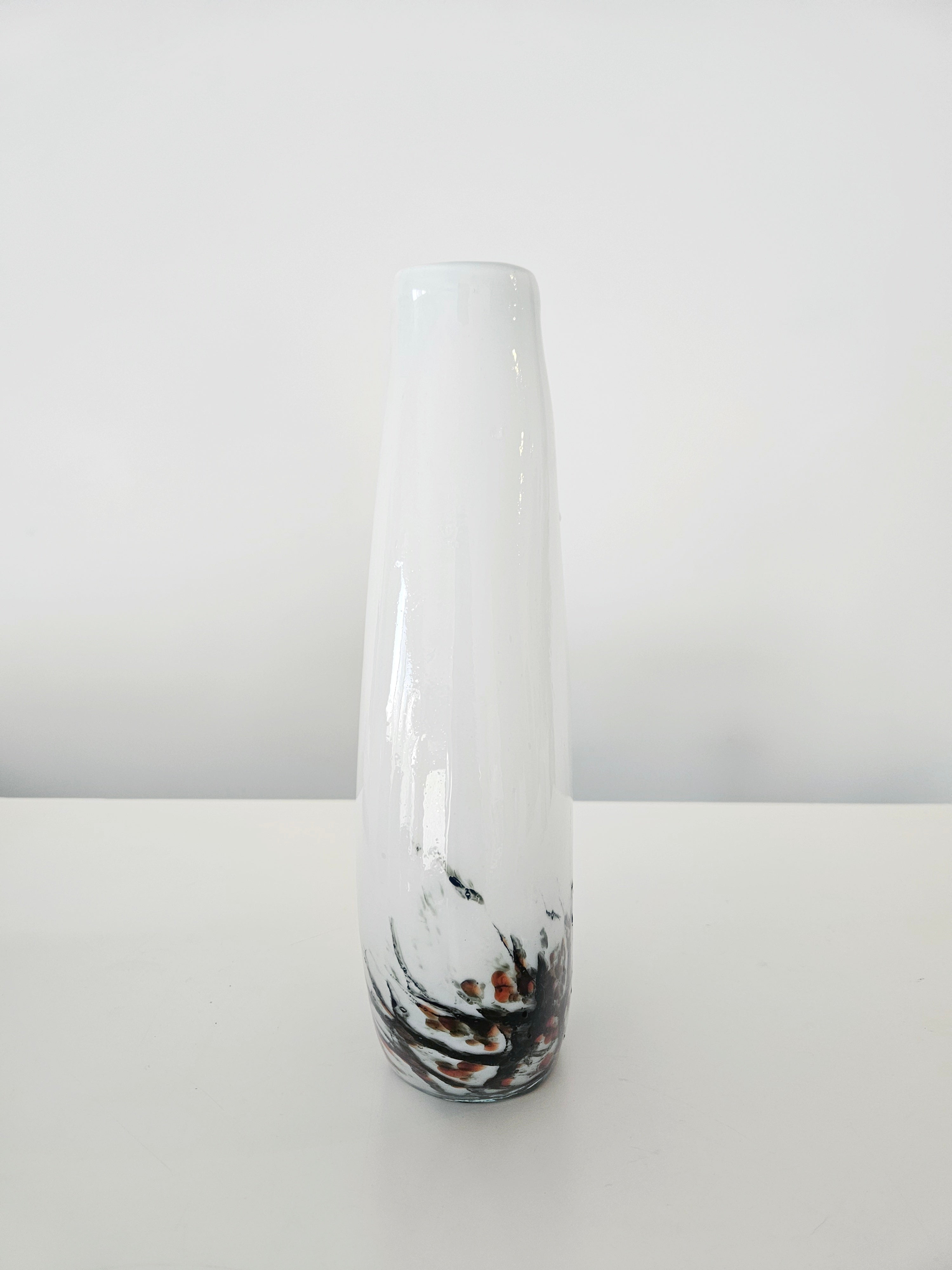 Tall cylindrical vase with black and orange abstract design on a white background