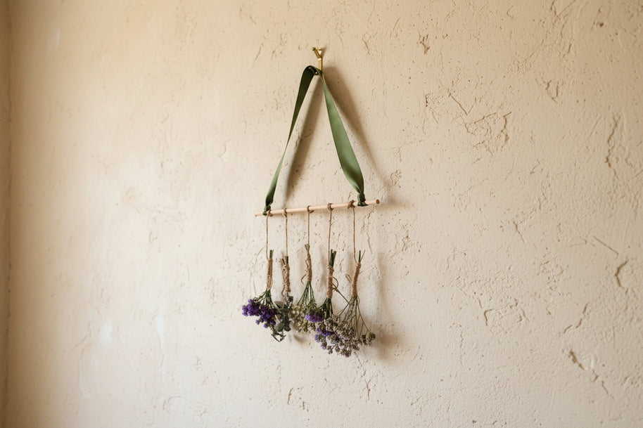 Decorative wall hanging with green ribbon and small bouquets of flowers on a white background