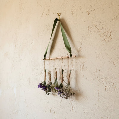 Decorative wall hanging with green ribbon and small bouquets of flowers on a white background