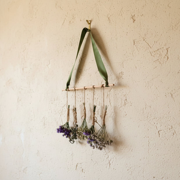 Decorative wall hanging with green ribbon and small bouquets of flowers on a white background