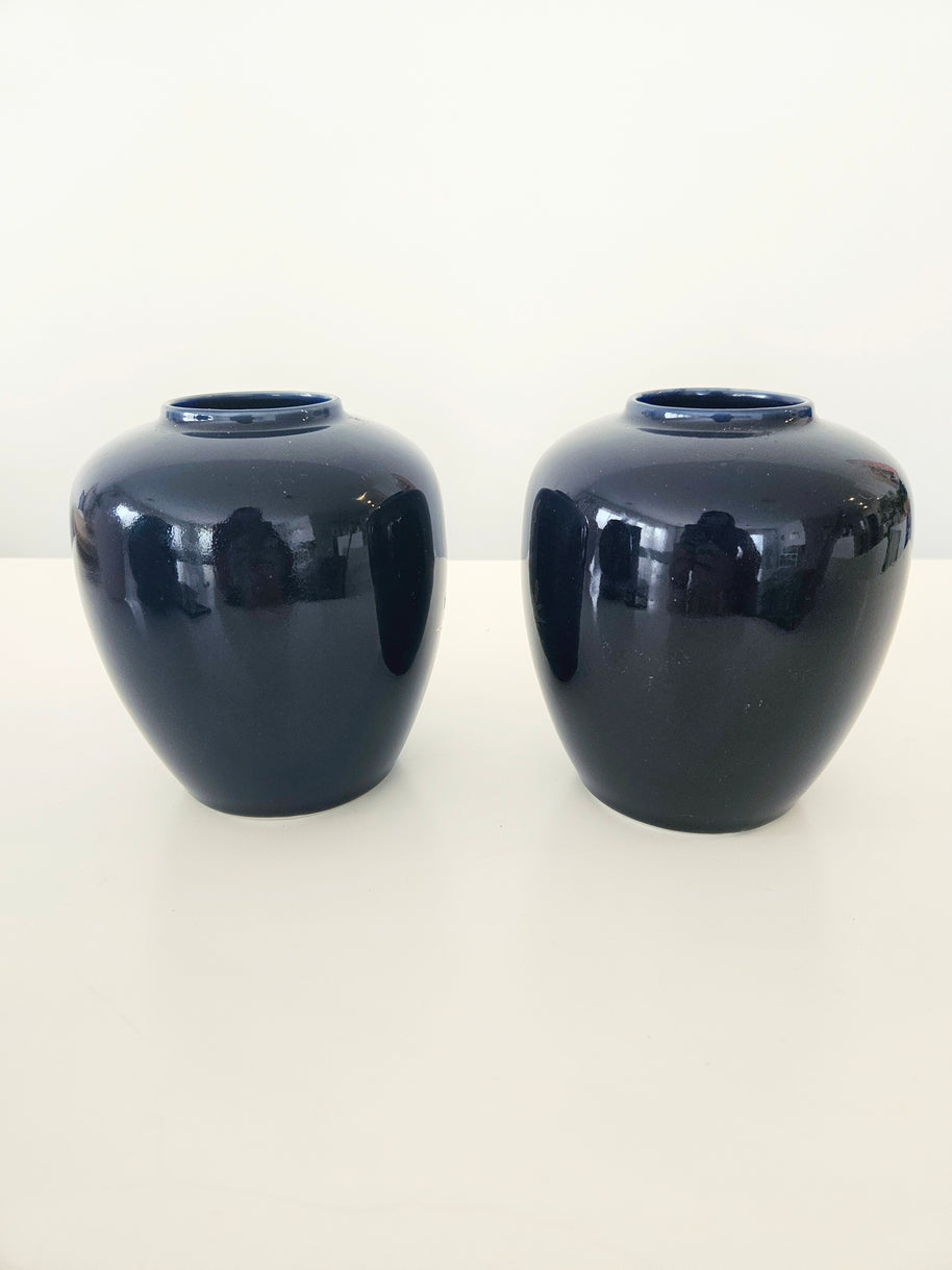 Two navy blue ceramic vases on a white background