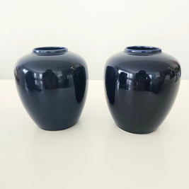 Two navy blue ceramic vases on a white background
