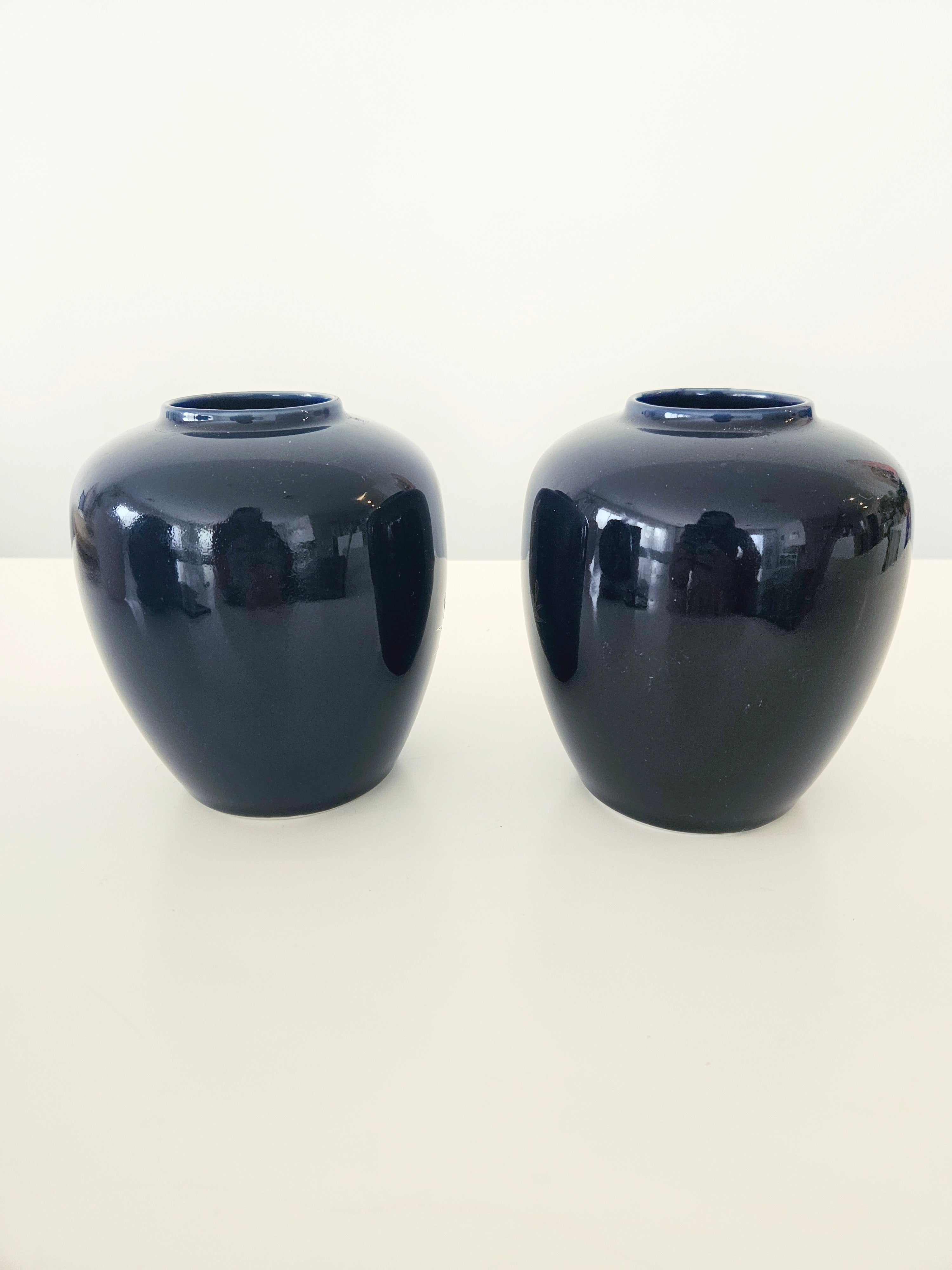 Two navy blue ceramic vases on a white background