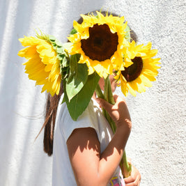 Child holding a bouquet of sunflowers against a white background