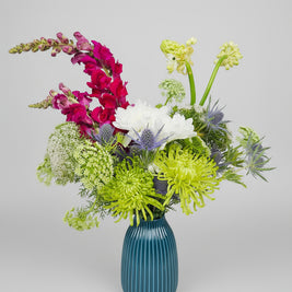 Floral arrangement in a blue vase on a light grey background