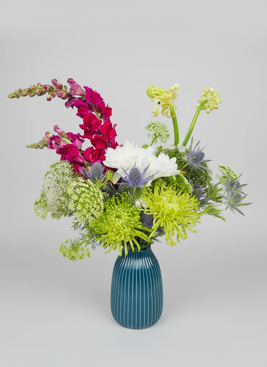 Floral arrangement in a blue vase on a light grey background