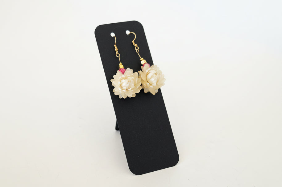 Pair of floral earrings on a black card with a white background