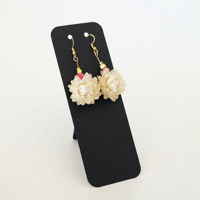 Pair of floral earrings on a black card with a white background