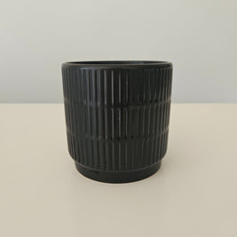 Side view of a black pot with a vertical pattern on a white background