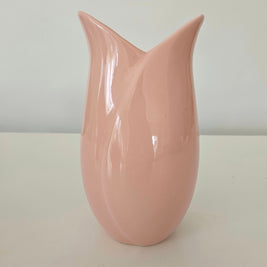 Pink tulip-shaped vase on a white surface with a light gray background