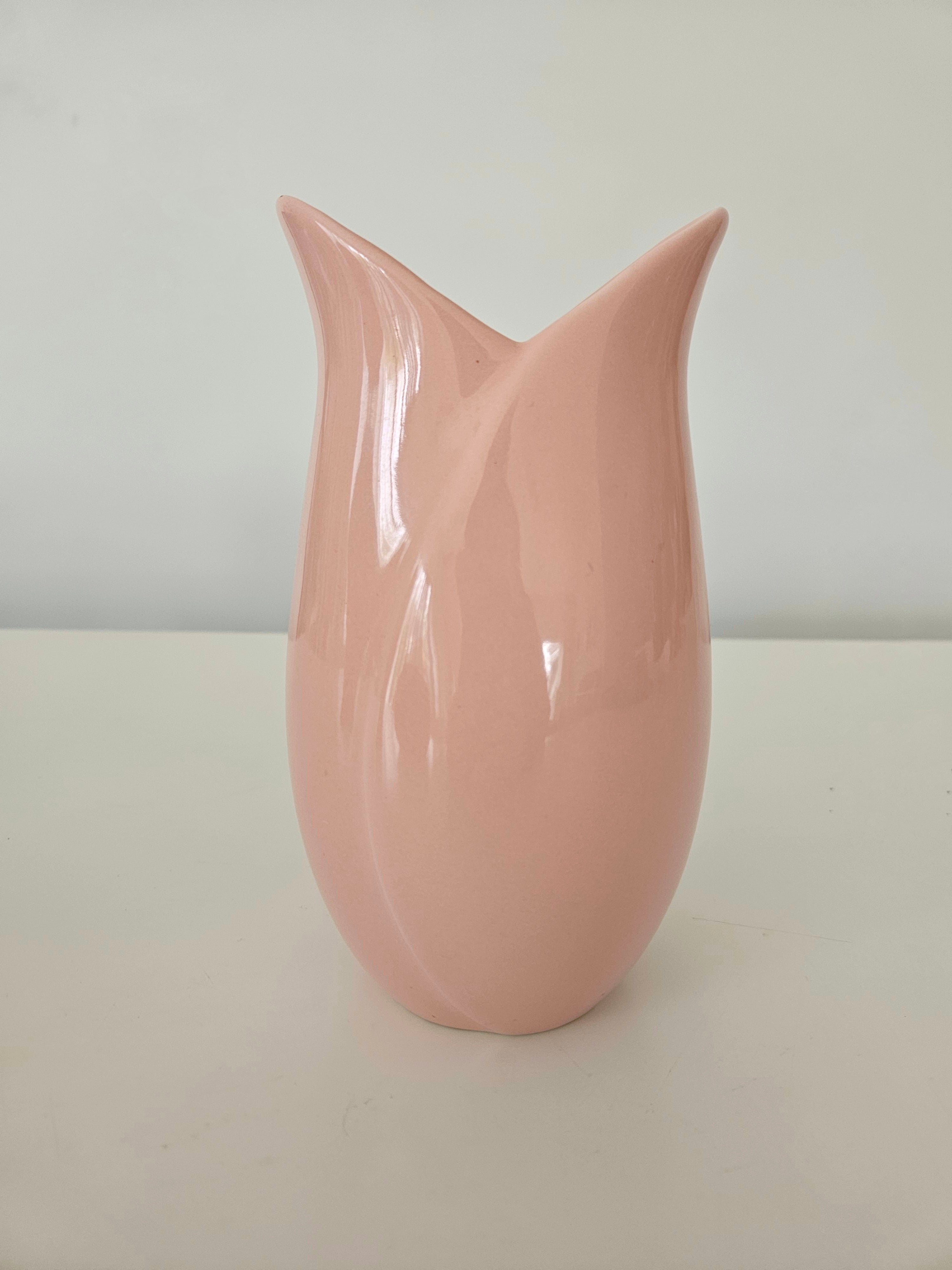 Pink tulip-shaped vase on a white surface with a light gray background