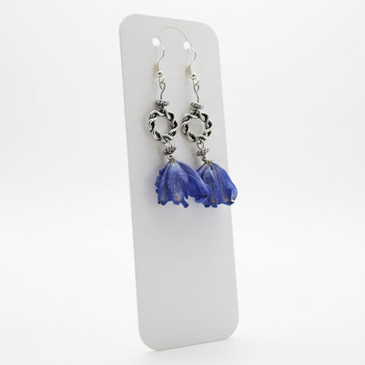 Silver earrings with blue flower pendants on a white card