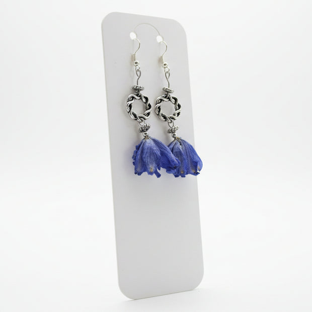 Silver earrings with blue flower pendants on a white card